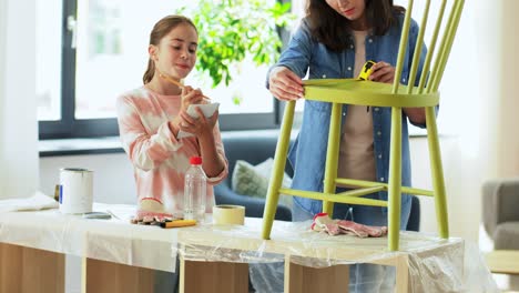 Concepto-De-Familia,-Bricolaje-Y-Mejoras-Para-El-Hogar-Feliz-Madre-Sonriente-E-Hija-Con-Regla-Midiendo-Una-Vieja-Silla-De-Madera-Para-La-Renovación-En-Casa