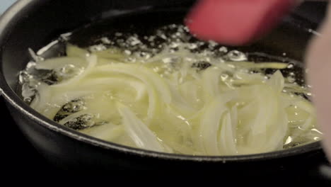 pouring-chopped-onion-slices-onto-a-frying-pan-with-hot-oil