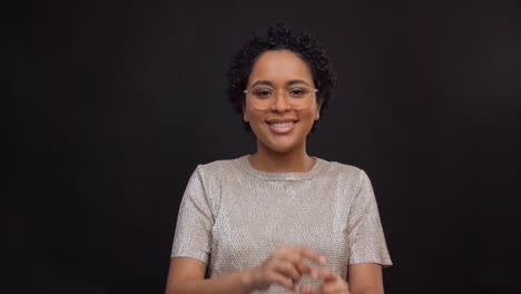 Concepto-De-Ocio-Y-Gente-Feliz-Mujer-Afroamericana-Con-Gafas-Bailando-Y-Dibujando-El-Corazón-En-El-Aire-Con-Los-Dedos-Sobre-Fondo-Negro