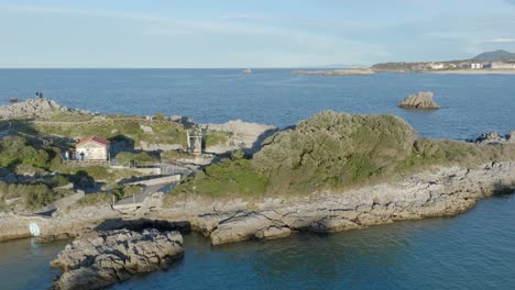 Aerial-establishing-shot-of-Rocky-Peninsula-revealing-El-sable-beach-in-Isla-Quejo,-Cantabria