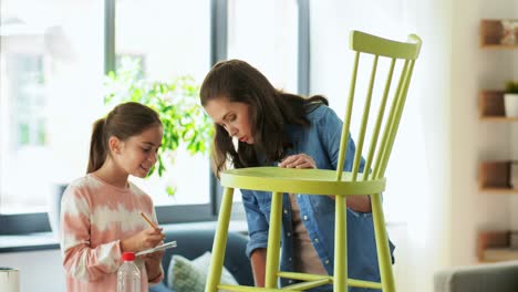 Concepto-De-Familia,-Bricolaje-Y-Mejoras-Para-El-Hogar-Feliz-Madre-Sonriente-E-Hija-Con-Regla-Midiendo-Una-Vieja-Silla-De-Madera-Para-La-Renovación-En-Casa