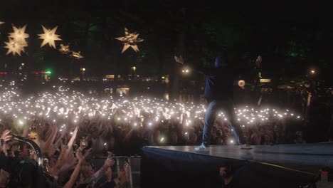 Hans-Philip-from-Ukendt-Kunstner,-performing-at-Skanderborg-festival-in-Denmark,-in-front-of-a-large-crowd-waving-their-flashlights-in-the-air