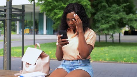 technology,-education-and-people-concept--happy-smiling-african-american-student-girl-with-textbook-calling-on-smartphone-in-city