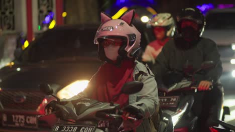 Mujer-Joven-Conduciendo-Una-Motocicleta-Con-Un-Casco-Con-Orejas-De-Gato-En-Medio-Del-Tráfico-Urbano-De-Indonesia