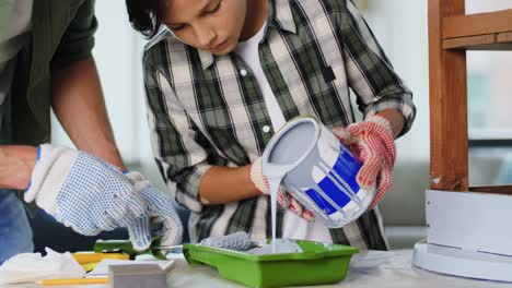 Concepto-De-Renovación,-Bricolaje-Y-Mejoras-Para-El-Hogar-Padre-E-Hijo-En-Guantes-Con-Rodillo-De-Pintura-Pintando-Una-Vieja-Mesa-De-Madera-En-Color-Gris-En-Casa