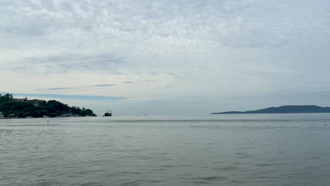 Calm-ocean-view-in-Cartagena,-Colombia-with-distant-boat-and-cloudy-sky