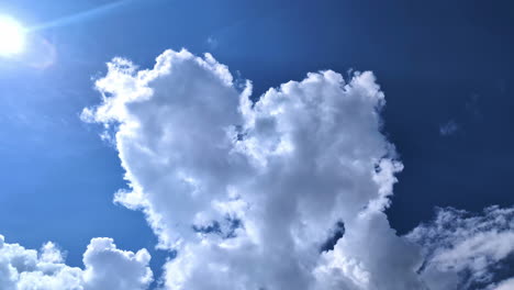 Heart-shape-clouds-and-sunshine-in-blue-sky,-view-from-bellow