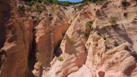 Aerial-ascent-inside-a-gully-geological-formation-with-red-rock-pinnacles