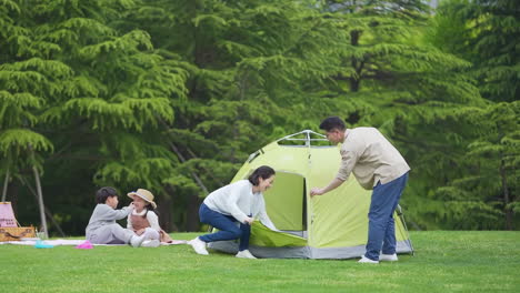 Happy-family-in-the-outdoor-outing-having-a-picnic-in-the-park,-concept-of-destination,-family-travel-and-summer-vacation-or-holidays