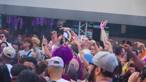 Energetic-crowd-with-raised-hands-at-outdoor-pride-festival,-showcasing-diversity-and-celebration