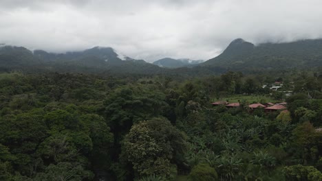 Toma-Aérea-De-La-Naturaleza-Costarricense-Con-Montañas-Brumosas-Y-Pequeñas-Casas-Al-Fondo-Tomada-Desde-Un-Dron