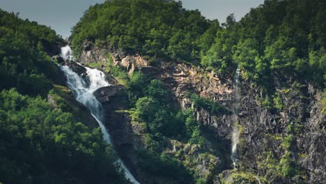 A-miniaturized-waterfall-cascaded-over-the-forest-covered-steep-shores-of-Naeroy-Fjord