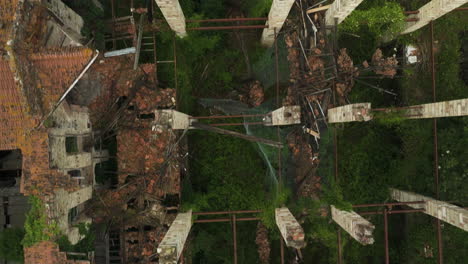 Abandoned-ceramic-factory-overgrown-with-greenery,-aerial-view