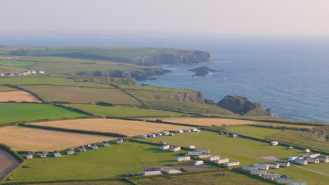 Aerial-view-of-Treyarnon-Bay-Caravan-Park-near-coastline-with-cliffs-and-coves