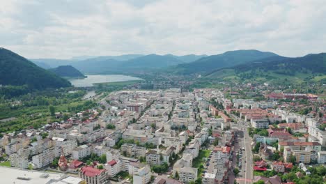 A-scenic-town-nestled-between-green-hills-and-a-winding-river-on-a-cloudy-day,-aerial-view