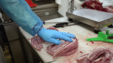 Beef-Navel-meat-being-cut-by-worker-with-a-knife-at-a-meat-processing-plant,-Close-up-shot