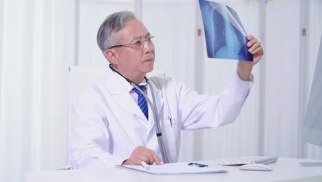 Medicine-middle-age-doctor-man-using-stethoscope-Wearing-white-coat,-stethoscope-standing-with-happy-face-smiling-looking-at-x-rays-with-hand,-successful-treatment-concept