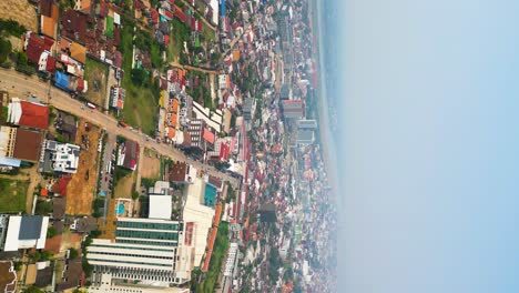 Vertical-rise-up-aerial-shot-of-Vientiane-cityscape-the-capital-of-Laos,-revealing-vibrant-rooftops-adorned-over-the-residential-area