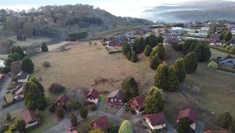 Drone-descending-over-amazing-landscape-showing-a-Swiss-Style-Village-in-Tasmania,-Australia