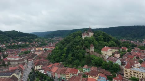 Una-Ciudad-Medieval-Con-Un-Castillo-En-Una-Colina-Verde,-Vista-Aérea