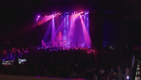 Music-artist-performing-in-a-dark-room-with-lots-of-lights-and-a-big-crowd