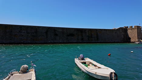 Barcos-De-Pesca-Amarrados-En-El-Puerto-De-La-Muralla-De-Corinto,-Grecia,-Atracción-Turística-Con-Cielo-Despejado