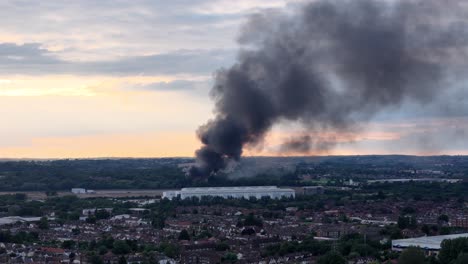 Vista-Aérea-De-Un-Edificio-Abandonado-En-Cheshunt,-Con-Una-Nube-De-Cenizas-En-Llamas-Y-En-órbita-Alrededor-De-La-Ciudad-Industrial-De-Hertfordshire