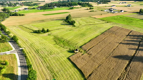 Aerial-view-of-a-combine-harvester-harvesting-a-large-field,-creating-distinct-rows---village-landscape