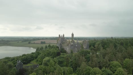 Historical-Gothic-Style-Of-Dromore-Castle-On-The-Hill-With-Lake-Co-At-Distance-In-Limerick,-Ireland