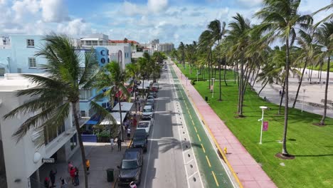 Walking-Pedestrian-on-sidewalk-at-Ocean-Drive-with-palm-trees-and-colorful-houses