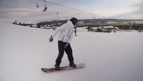 Snowboarder-Haciendo-Nose-Slide-En-Un-Tubo-Que-Se-Desliza-A-Través-De-La-Capa-De-Nieve