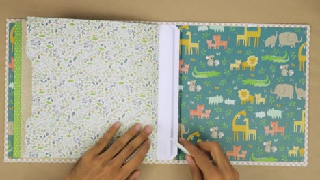 Hands-creating-a-colorful-scrapbook-with-patterned-papers-for-a-baby