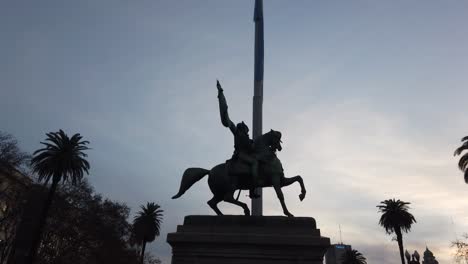 Independence-statue-at-Buenos-Aires-city-dusk-skyline,-man-in-a-horse-with-flag-national-symbol-of-Argentine