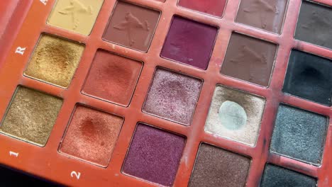 Brush-blending-colorful-eyeshadow-on-palette,-close-up-shot