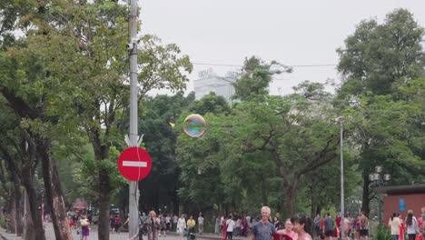 Soap-bubble-float-con-air,-hand-try-to-reach,-at-public-area-slow-motion