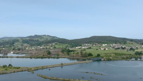 Drohnenüberflug-über-Die-Flussmündung-In-Richtung-Einer-Kleinen-Siedlung,-Umgeben-Von-Grüner-Landschaft,-Santona,-Spanien