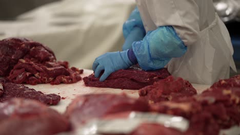 Skirt-steak-being-trimmed-by-worker-with-a-large-knife-at-a-meat-processing-plant,-Close-up-shot