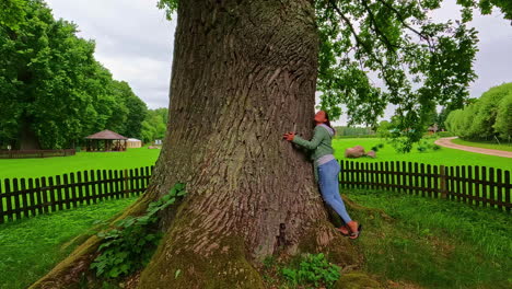 Static-shot-of-woman-hugging-giant-trunk-of-a-strong-tall-tree