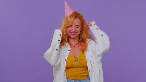 Redhead-girl-in-festive-hat-shouting-raising-fists-in-gesture-I-did-it-celebrating-success,-winning