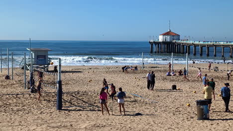 Static-shot-of-tourists-playing-volleyball-on-Manhattan-beach-during-afternoon-in-California,-USA