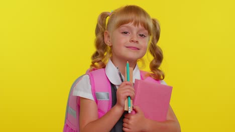 Cheerful-funny-schoolgirl-kid-with-books-dressed-in-uniform-wears-backpack-smiling-looking-at-camera