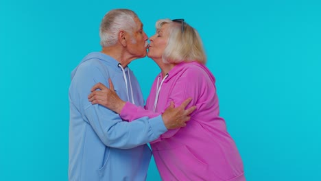 Romantic-senior-couple-man-woman-grandparents-making-lots-of-kisses-looking-at-camera-and-smiling