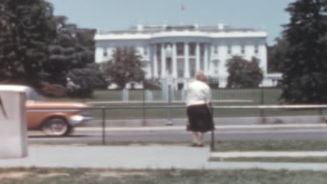 Una-Mujer-Está-Parada-En-La-Calle-Con-Una-Casa-Blanca-Al-Fondo-En-Washington-D.C.