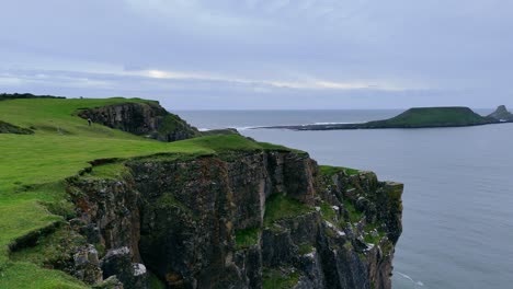 Worm’s-Head,-dragon’s-back-rising-from-sea,-stretches-towards-Rhossili-Bay