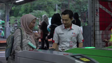 Mujer-Entrando-A-La-Estación-De-Tren-De-Rawa-Ubuntu-Con-La-Ayuda-De-Un-Oficial-En-Tangerang-Selatan,-Indonesia