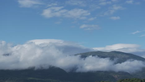 Vuelo-Con-Drone-En-El-Valle-Del-Tiétar-ávila-En-Una-Mañana-Donde-Vemos-Con-Un-Giro-De-La-Cámara-Que-Las-Nubes-Se-Han-Pegado-A-Las-Montañas-También-Hay-Nubes-Bajas-Y-Un-Cielo-Azul,-Precioso-Paisaje