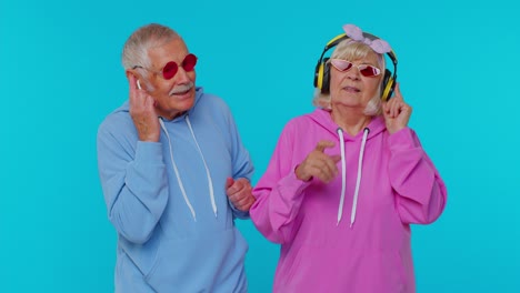 Senior-stylish-grandparents-pensioners-listening-music-via-headphones,-dancing-disco-fooling-around