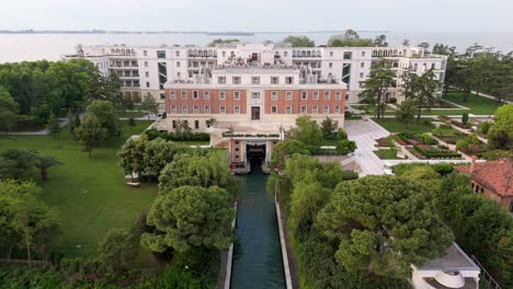 Aerial-flyover-of-luxury-hotel-and-lush-garden-on-private-island-in-Venice,-Italy