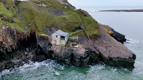 Abandoned-boathouse,-rocky-coast,-Worms-head,-Rhossili-Bay,-Wales,-aerial