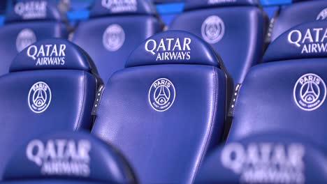 Blue-folded-up-seats-with-Qatar-airways-logo-at-empty-French-Soccer-stadium-of-Parc-des-Princes,-Close-up-shot